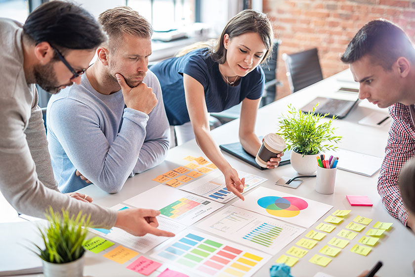 Four people consult charts at a conference table